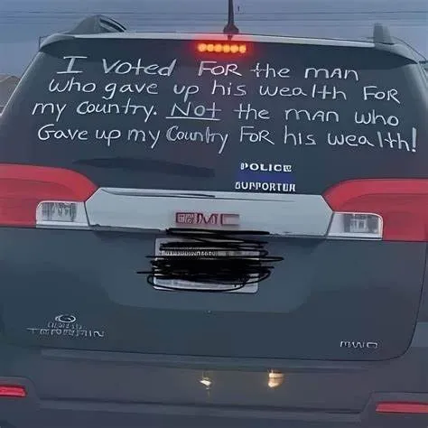 A photograph of a black SUV’s rear window displays a handwritten message in white paint